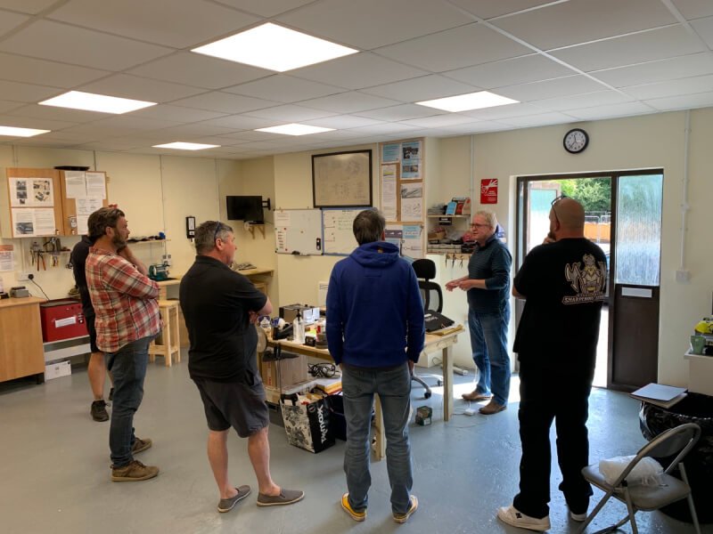 Blade sharpening course in action. Four men, three men with backs to viewer. Sharp Knives Sales and Training Ltd. Scissor and Blade sharpening training courses. Bath, Radstock